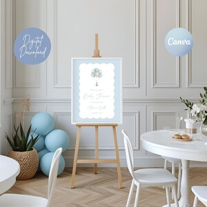 Pode incluir: Uma placa de chá de bebê em um cavalete de madeira. A placa tem uma borda de bolinhas azul claro e apresenta um gráfico de balão e âncora. O texto na placa diz "This is for a Baby Shower" e inclui o nome e a data. Um gráfico de "Download Digital" está no canto superior esquerdo.