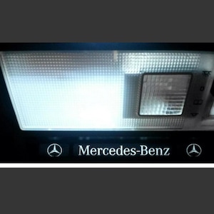 以下が含まれることがあります： 白いレンズとメルセデス・ベンツのロゴが付いた黒いオーバーヘッドライト。ライトには右側に白いプラスチック製のスイッチがあります。
