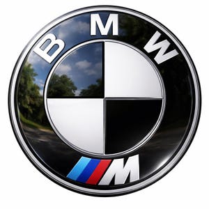 Könnte beinhalten: Ein glänzendes BMW-Emblem mit einem schwarzen Außenring und einem silbernen Innenring. Die Mitte zeigt ein Vier-Quadranten-Design in Schwarz, Weiß und Silber mit einer Himmels- und Baumreflexion. Die Buchstaben "BMW" sind weiß. Das "M"-Logo befindet sich unten.
