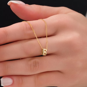 May include: A gold chain necklace with a small, gold, letter 'B' pendant.