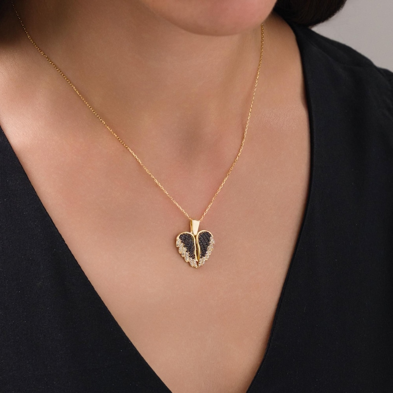 May include: A gold chain necklace with a black and white heart pendant. The heart pendant has a detailed design with small stones.