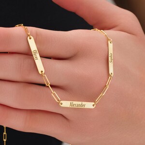 May include: Gold chain necklace with three personalized nameplates. The nameplates are engraved with the names "Oliver", "Alexander", and "Sophia".