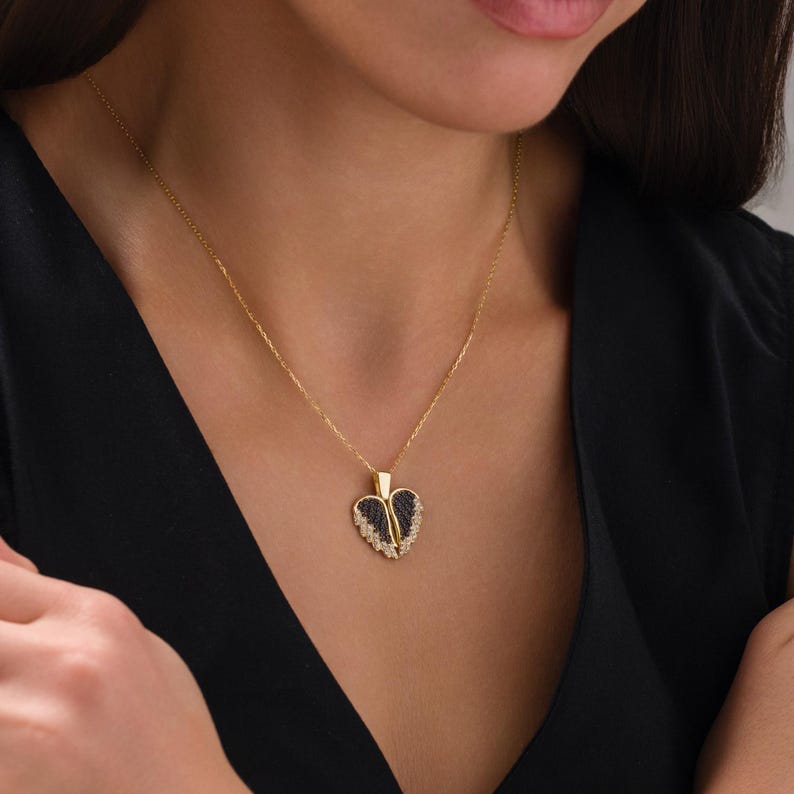 May include: A gold chain necklace with a black and gold heart pendant. The heart pendant is adorned with small sparkling stones.