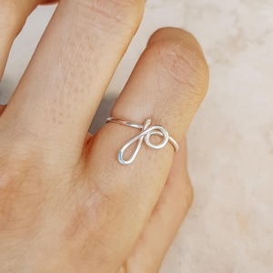 May include: A white ceramic mug with a black handle and the text "But First, Coffee" in a handwritten style. The mug is on a white surface. The mug is approximately 4 inches tall.