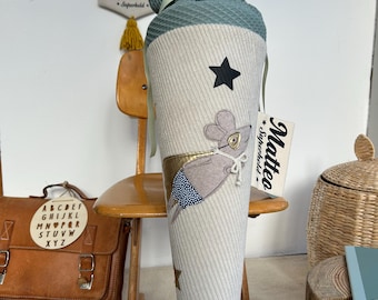 May include: A gray and white fabric cone with a mouse superhero design. The cone has black stars and a tag that says "Mattea Superhero".