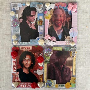 May include: Four rectangular photo cards decorated with various stickers and charms. The cards feature portraits of individuals, Japanese text, and embellishments including plastic flowers, hearts, bows, and glitter-filled resin shapes.