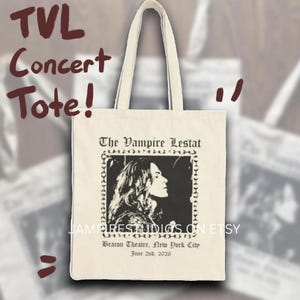 May include: A cream-colored canvas tote bag featuring a black graphic print. The design includes the text The Vampire Lestat, a profile illustration of a person, and the text Beacon Theatre, New York City, June 2nd, 2026, enclosed in a chain border.