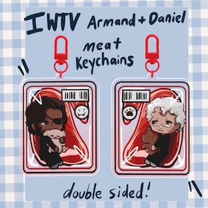 Puede incluir: Dos llaveros de acrílico transparente con los personajes de dibujos animados Armand y Daniel, cada uno en un paquete rojo con forma de carne con código de barras e icono. Cierres de langosta rojos. Texto: IWTV Armand + Daniel meat Keychains double sided!