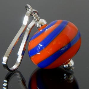 May include: A silver key chain with a blue and orange glass bead. The bead has a swirl pattern.