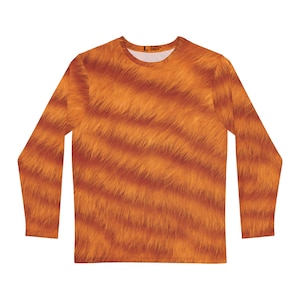 Op de afbeelding: Oranje shirt met lange mouwen en een imitatiebontpatroon. Het shirt heeft een ronde hals en een herhalend patroon van oranje en bruine strepen, wat een textuureffect creëert. Het shirt is effen van kleur en heeft lange mouwen.