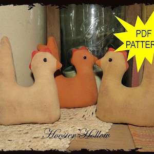 May include: Three handmade fabric chicken figurines in shades of tan and orange, with red comb details and black eyes. The chickens are arranged on a lace doily. A yellow starburst graphic reads "PDF PATTERN". The text "Hoosier Hollow" is below.