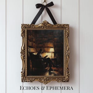 May include: A framed print featuring a person reading in a library, illuminated by a lamp. The print is in an ornate gold frame and is suspended by a black ribbon. The text "ECHOES & EPHEMERA" is at the bottom of the frame.
