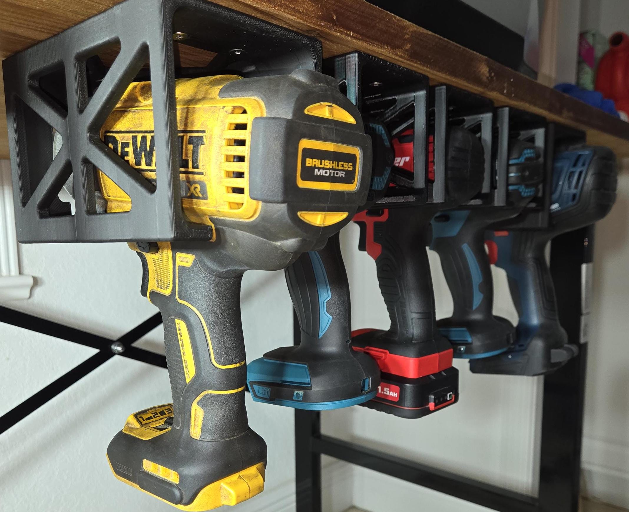 A set of four power tool hangers mounted on a shelf, showcasing a Dewalt brushless motor drill and three other drills.