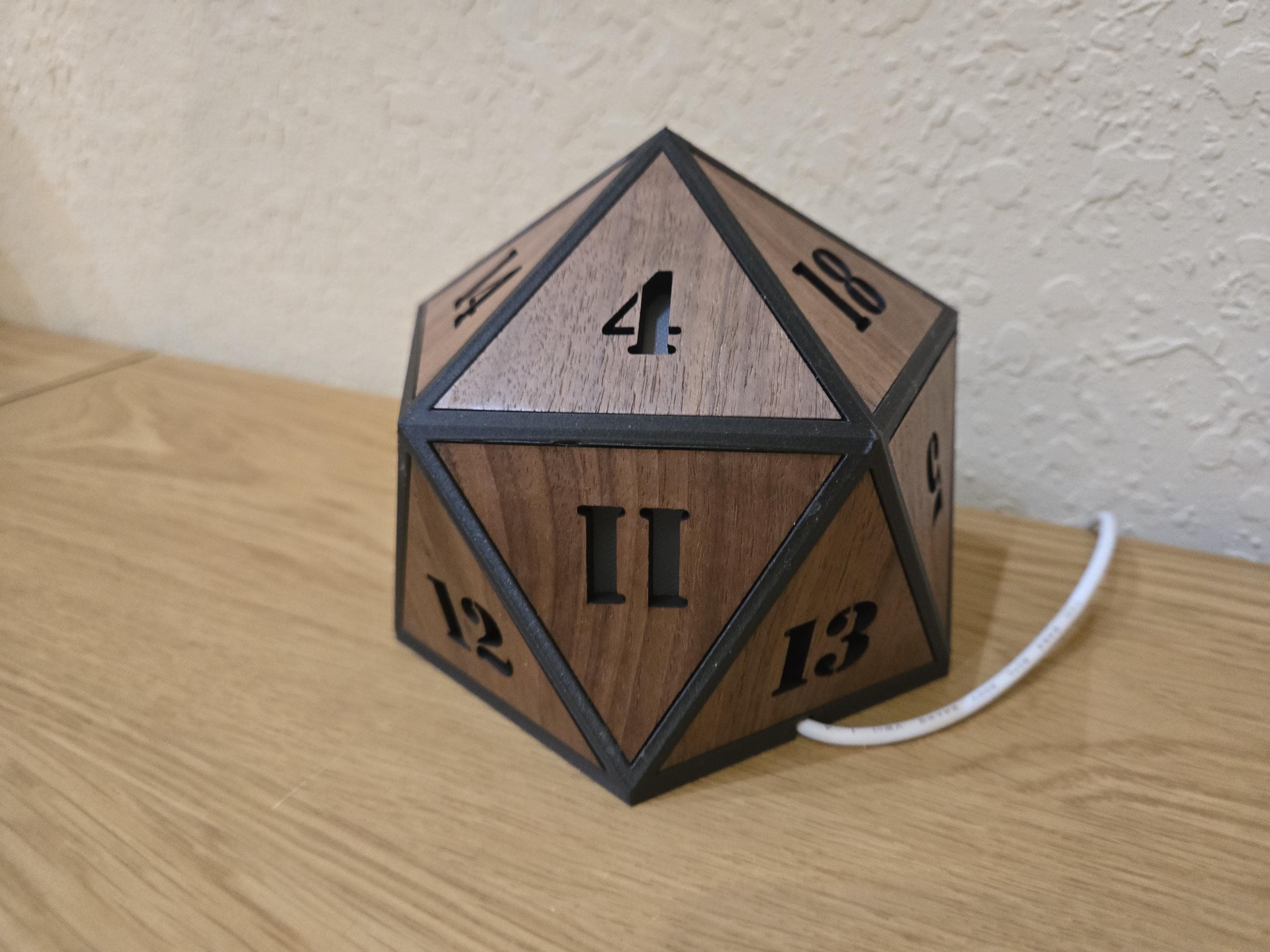Unlit rear view of the walnut dice lamp showing numbered triangular panels and its white power cord.