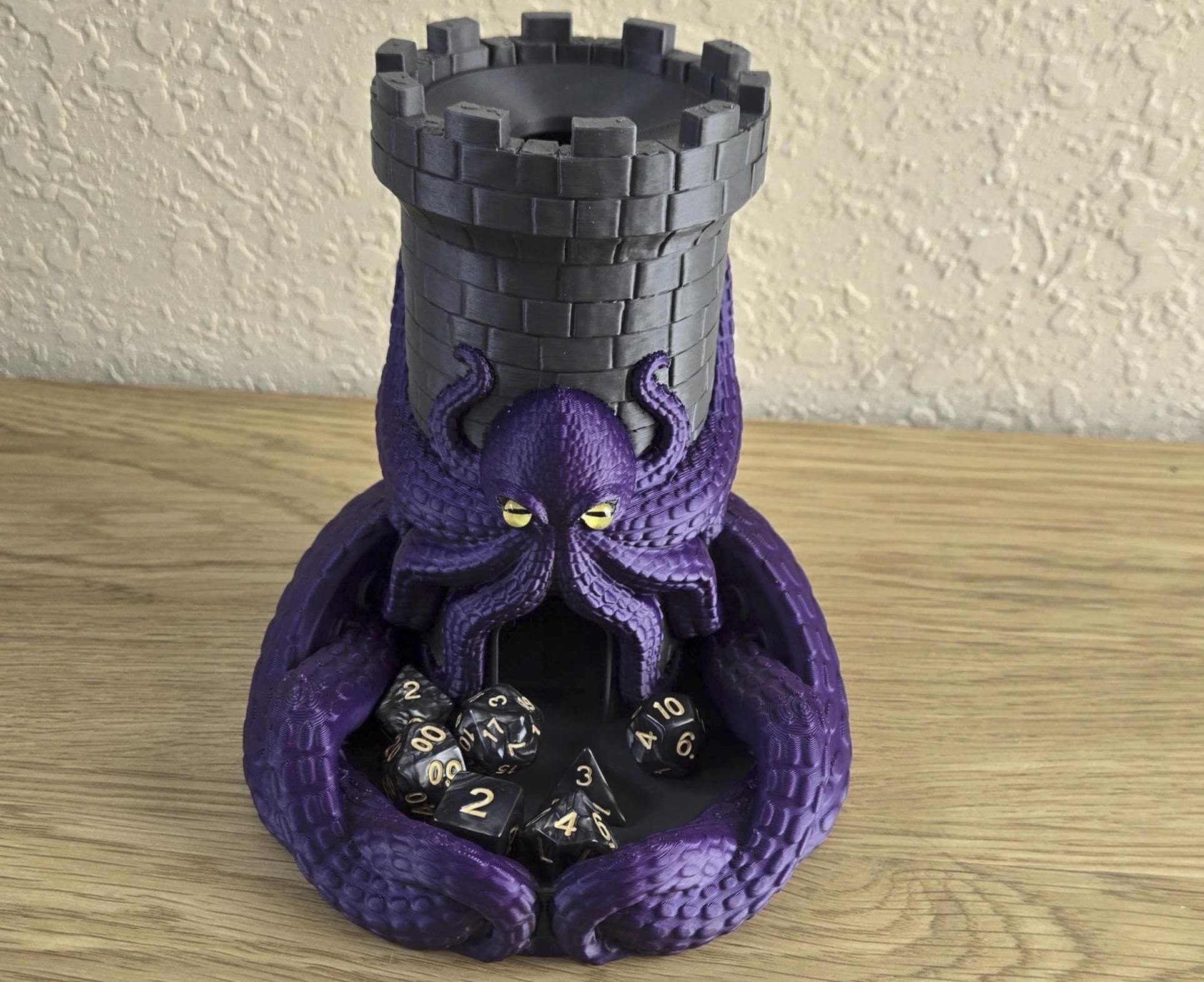 A Kraken Castle Dice Tower with a purple octopus design, featuring a black tower and a collection of black dice with gold数值s.