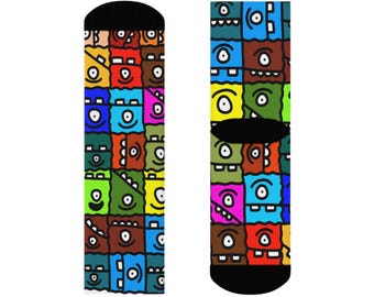 Könnte beinhalten: Ein Paar bunte Socken mit einem sich wiederholenden Muster aus Cartoon-Monstergesichtern in verschiedenen Farben. Die Socken haben schwarze Fersen und Zehen. Die Monstergesichter sind in Quadraten und haben unterschiedliche Ausdrücke.