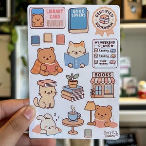 Puede incluir: Una hoja de pegatinas con ilustraciones tem&aacute;ticas de lectura. Los dise&ntilde;os incluyen un oso con un libro, un gato leyendo, un conejito durmiendo y una taza de caf&eacute;. El texto incluye "Library Card", "Book Lovers" y "Certified Bookworm."