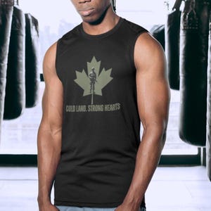 May include: Black sleeveless shirt featuring a green maple leaf design with a soldier silhouette. The text "COLD LAND, STRONG HEARTS" is printed below the graphic. The shirt is made of a dark fabric.