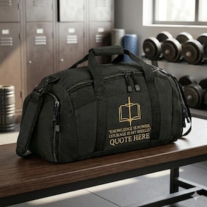 Könnte beinhalten: Schwarze Sporttasche mit goldenem Emblem, das ein offenes Buch und ein Schwert zeigt. Die Tasche hat einen oberen Griff, einen Schultergurt und mehrere Reißverschlussfächer. Text auf der Tasche: "KNOWLEDGE IS POWER, COURAGE IS MY SHIELD. QUOTE HERE."