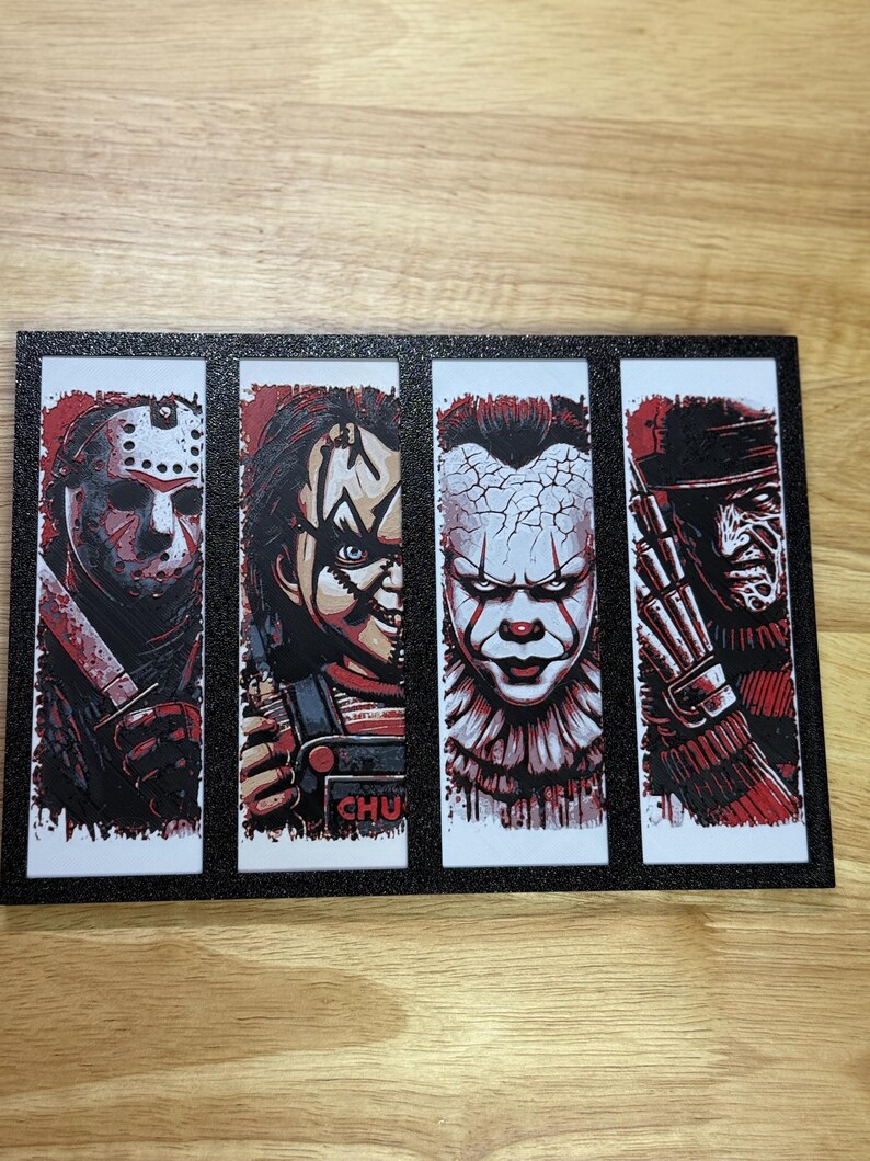 May include: A framed art print featuring four horror movie characters: Jason Voorhees, Chucky, Pennywise, and Freddy Krueger. Each character is depicted in a vertical panel with a red and white colour scheme. The frame is black with glitter.
