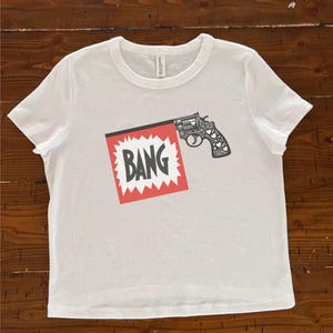 Bang! グラフィック クロップドTシャツ – コミックポップアート Y2K ベビーTシャツ | エッジの効いた漫画風ピストルデザイン | レトロストリートウェア | フェスティバルフィット | カスタムギフトアイデア