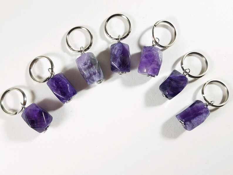 May include: Seven amethyst stone keychains with silver rings. Each keychain features a different shaped amethyst stone.