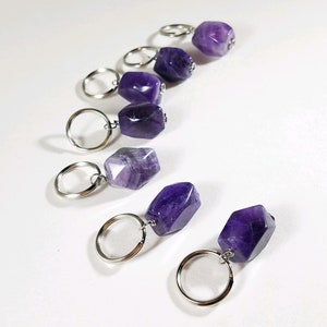 May include: Seven amethyst stone keychains with silver key rings. The amethyst stones are various shades of purple and have a faceted, geometric shape.