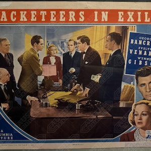 May include: A vintage movie poster for the film "Racketeers in Exile" featuring a group of actors in a scene from the film. The poster includes the title of the film, the names of the actors, and the Columbia Pictures logo.