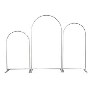 May include: A set of three silver-colored metal arch frames of varying heights, each featuring a rounded top and a flat base stand. The structures are constructed from thin, tubular metal components connected to form three distinct arched displays.