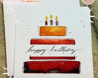 May include: A watercolor birthday card with a hand-painted cake with three candles and the words "happy birthday" written in gold script. The card has a white background with gold and red speckles.
