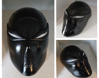 May include: A glossy black full-face mask featuring a perforated pattern across the forehead and mouth area. The mask includes angular eye openings with white mesh inserts, creating a distinct look with a smooth, reflective finish throughout.