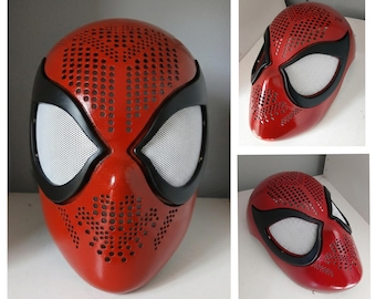 May include: A glossy red full-face mask featuring a perforated pattern across the forehead and chin areas. The mask includes large, almond-shaped eye openings outlined in black, fitted with white mesh lenses, and a smooth, rounded surface finish.