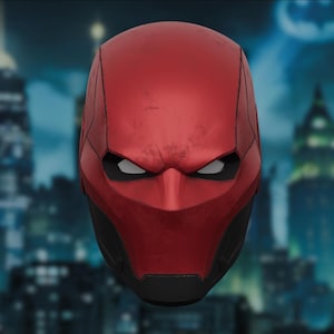 May include: A red and black helmet with a weathered appearance, showcasing a stern, angular design. The helmet features white eye openings and a pronounced, pointed nose. The design suggests a superhero or comic book theme.