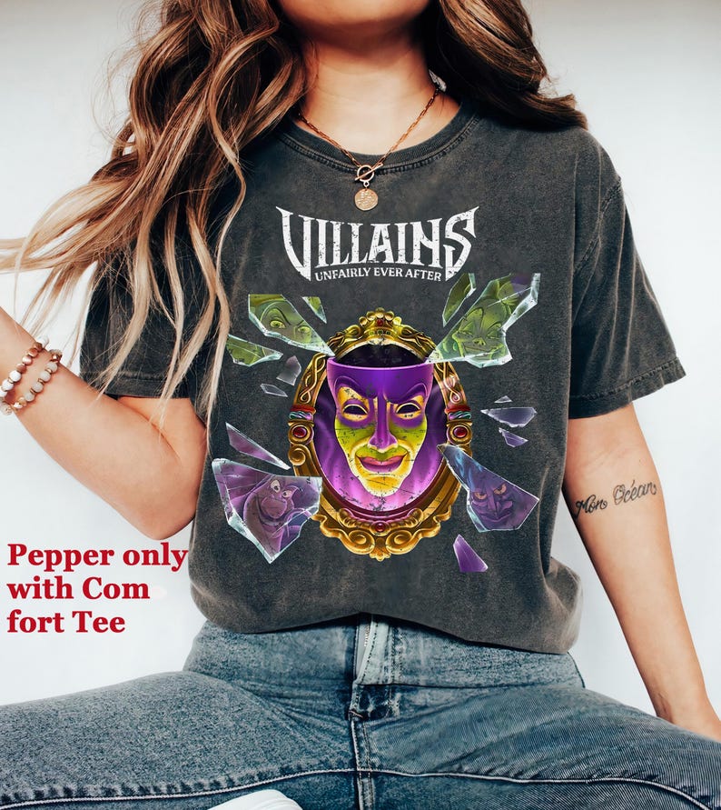 Puede incluir: Camiseta gris oscuro con la palabra "Villains" sobre un dise&ntilde;o de espejo roto con una m&aacute;scara morada y amarilla. El texto "Unfairly Ever After" est&aacute; debajo. Es una camiseta c&oacute;moda.