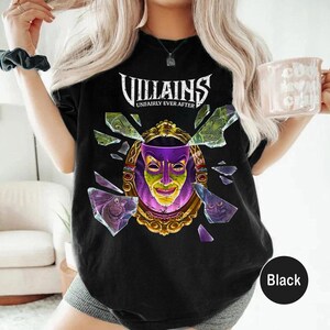 Puede incluir: Camiseta negra con el texto "VILLAINS UNFAIRLY EVER AFTER" sobre un dise&ntilde;o de espejo roto. El espejo revela una m&aacute;scara morada y verde. La camiseta es de cuello redondo.