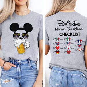 May include: A heather gray t-shirt featuring a Mickey Mouse graphic wearing sunglasses and holding a beer stein. The back of the shirt displays the text "Drinking Around The World Checklist" with country flags.