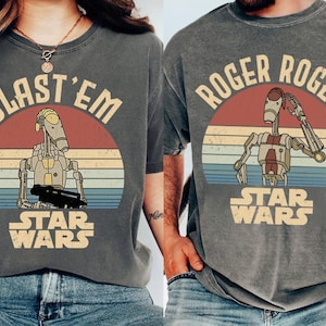 以下が含まれることがあります： スターウォーズのグラフィックがプリントされた2枚のグレーのTシャツ。1枚は「BLAST 'EM」とドロイドのイラストとスターウォーズのロゴ。もう1枚は「ROGER ROGER」とドロイドのイラストとスターウォーズのロゴ。