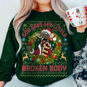 May include: A dark green long-sleeve sweatshirt featuring a graphic of a cartoon rat wearing a Santa hat and scarf, holding a gift inside a holiday wreath. The text reads "GOD SAVE MY LITTLE BROKEN BODY" in red block letters above and below.