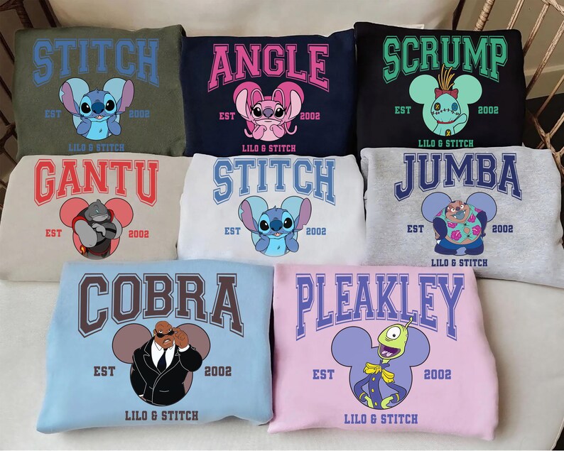 May include: Nine different coloured sweatshirts featuring a variety of cartoon characters from the Disney film Lilo & Stitch. Each sweatshirt features a different character, including Stitch, Angle, Scrump, Gantu, Jumba, Cobra, and Pleakley. The sweatshirts are all in a college-style design with the character's name and the year 2002 printed on them.