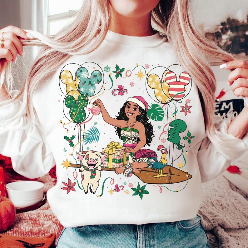 K&ouml;nnte beinhalten: Wei&szlig;es Sweatshirt mit einer festlichen Illustration. Es zeigt eine Zeichentrickfigur, Mickey Mouse-Ballons und Weihnachtsdekorationen. Das Design umfasst ein Schwein mit Schal, ein Huhn und verpackte Geschenke.