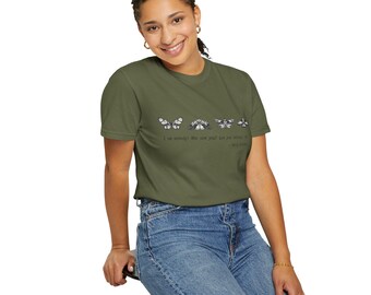May include: A woman wearing a green t-shirt with a graphic of butterflies and the text "I am already! Do you see you? Are you waking up?"  The shirt has a crew neck and short sleeves.
