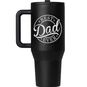K&ouml;nnte beinhalten: Ein mattschwarzer Edelstahlbecher mit passendem Deckel und einem stabilen Seitengriff. Die Vorderseite zeigt eine wei&szlig;e kreisf&ouml;rmige Grafik mit dem Text "BEST" oben, "Dad" in gro&szlig;er Schreibschrift in der Mitte und "EVER" unten.