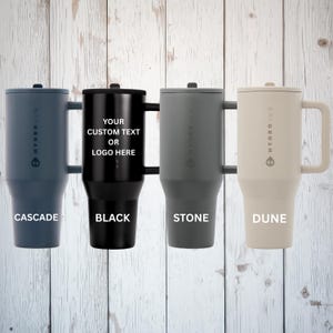 May include: Four insulated tumblers with handles, each featuring a lid and the HydroJug logo. The colors from left to right are cascade, black, stone, and dune. The black tumbler displays the text YOUR CUSTOM TEXT OR LOGO HERE.