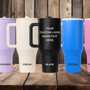 K&ouml;nnte beinhalten: F&uuml;nf hohe Isolierbecher mit Griffen, jeweils mit Deckel und konischem Boden. Die Farben von links nach rechts sind Lavendel, Creme, Schwarz, Blau und Pink. Der schwarze Becher zeigt den Text YOUR CUSTOM LOGO NAME/TEXT HERE.