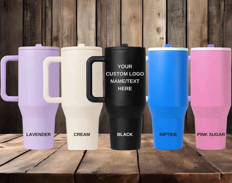 Puede incluir: Cinco vasos aislados en lavanda, crema, negro, azul y rosa. Cada vaso tiene un asa y una tapa. El vaso negro tiene el texto "YOUR CUSTOM LOGO NAME/TEXT HERE". Los otros vasos tienen los textos "LAVENDER", "CREAM", "RIPTIDE" y "PINK SUGAR".