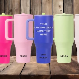 K&ouml;nnte beinhalten: F&uuml;nf isolierte Becher mit Griffen und Deckeln in den Farben Orchidee, Blush, Lime Rickey, Melone und Rosensand. Der mittlere blaue Becher tr&auml;gt den Text YOUR CUSTOM LOGO NAME/TEXT HERE. Jeder Becher ist mit seinem Farbnamen beschriftet.