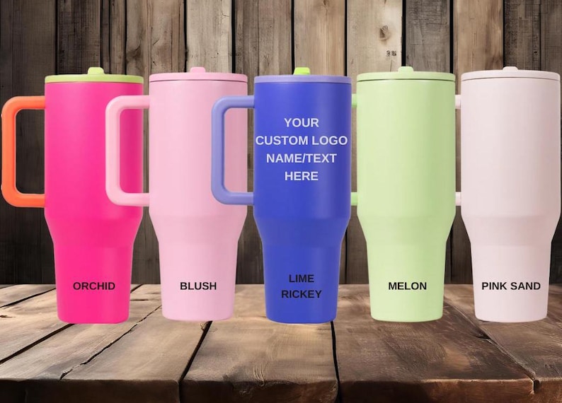 K&ouml;nnte beinhalten: F&uuml;nf isolierte Becher mit Griffen und Deckeln in den Farben Orchidee, Blush, Lime Rickey, Melone und Rosensand. Der mittlere blaue Becher tr&auml;gt den Text YOUR CUSTOM LOGO NAME/TEXT HERE. Jeder Becher ist mit seinem Farbnamen beschriftet.