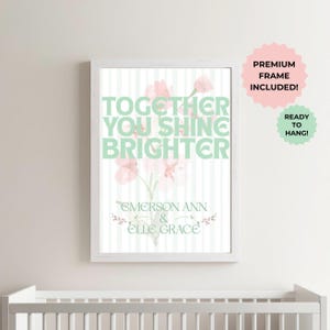 May include: A framed art print with the words "TOGETHER YOU SHINE BRIGHTER" in mint green, with a floral design and the names "EMERSON ANN & ELLE GRACE". The print is in a white frame and includes the text "PREMIUM FRAME INCLUDED!" and "READY TO HANG!"