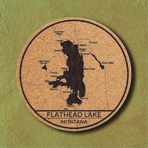 Puede incluir: Un posavasos redondo de corcho con un mapa detallado del lago Flathead en Montana, con pueblos y puntos de referencia etiquetados. El posavasos tiene un borde marrón oscuro y las palabras "Flathead Lake Montana" en la parte inferior.