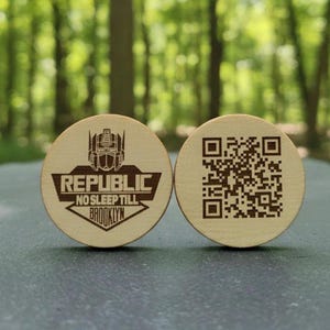 May include: Two round wooden tokens. One features a robot graphic and the text "REPUBLIC NO SLEEP TILL BROOKLYN". The other token has a QR code. Both tokens are light brown.